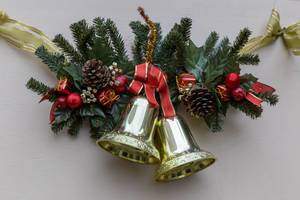 Weihnachtsschmuck für Haustür aus Tannenzweigen mit goldenen Glocken, Tannenzapfen und roten Geschenken