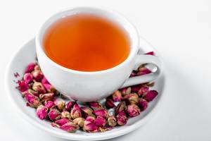 White Cup of tea and dried rose buds in saucer