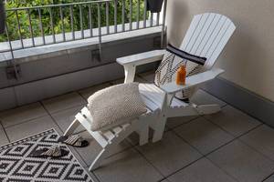 White deckchair - sun lounger -  with comfortable cushions, summer slippers and sun milk, on a balcony