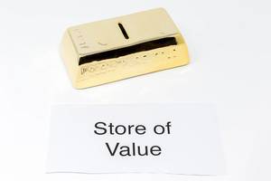 White paper with lettering STORE OF VALUE next to gold bars = gold as an investment object
