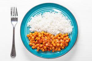 White rice and chickpeas in tomato sauce on white wooden background with fork. Top view (Flip 2019)