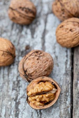 Whole and half walnuts on wooden background