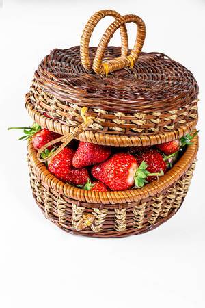 Wicker basket filled with fresh strawberries on white background