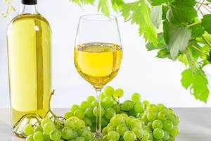 Wine background with ripe fresh grapes, full bottle and glass and green branches with leaves