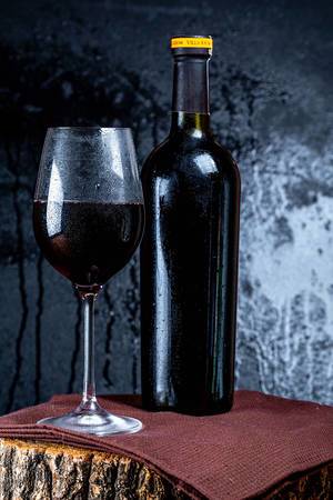 Wine bottle with wineglass red wine on dark background