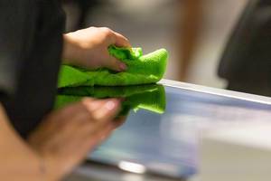 Woman cleans the kitchen surface with a green, dry cloth