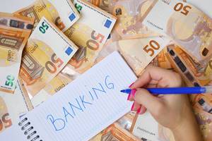 Woman hand writing Banking, 50 Euro banknotes background