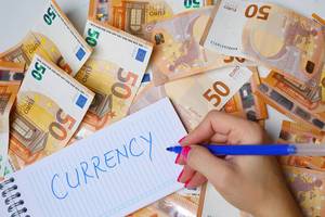 Woman hand writing Currency, 50 Euro banknotes background