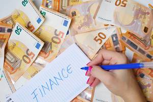 Woman hand writing Finance, 50 Euro banknotes background