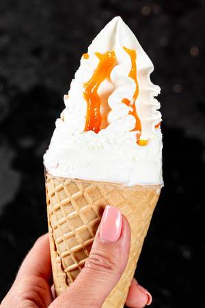 Woman holds ice cream with caramell topping