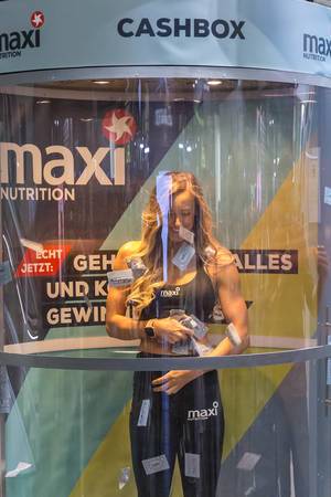 Woman in the maxi Nutrition Cashbox tries to catch cards at the fair Fibo in Cologne, Germany