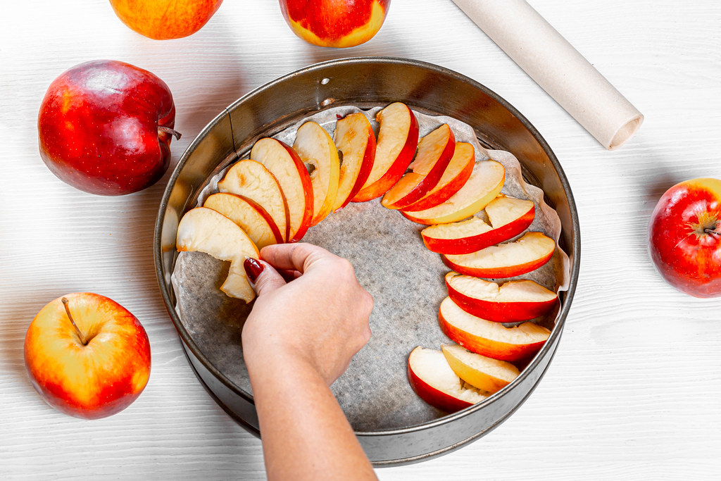 Woman lays slices of apples on a baking sheet. Home cooking concept