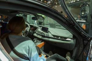 Woman sits inside the limited hybrid car BMW i8 Ultimate Sophisto Edition to look over the interior