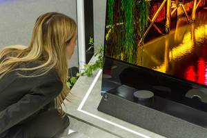 Woman takes a closer look at Metz Oleds AI screen of its 8K TV
