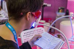 Woman tests teeth whitening system by Only Smile while she comfortably reads at Fibo in Cologne