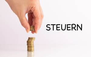 Womans hand picking up coins with Steuern text