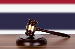 Wooden gavel and flag of Thailand