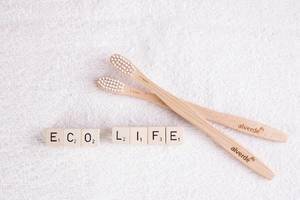 Wooden toothbrushes with eco life text on white towel