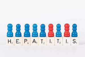 Word Hepatitis written on wooden blocks with pawns in various colors on white background