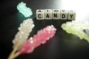 Würfel zeigen das Wort Candy - Süßigkeiten - umgeben von zuckerhaltigen Süßigkeiten in bunten Farben