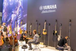 Yamaha Instrumentenvorstellung: Besucher spielen auf Akkustik-Gitarren und Bassgitarren