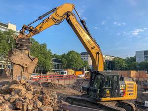 Yellow excavator works on a construction site for the new office tower "Wallarkaden" next to U-Rudolfplatz and Hahnentor in Cologne