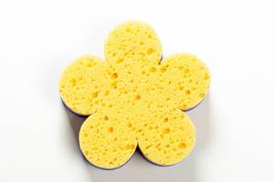 Yellow washcloth in the shape of a flower on white background