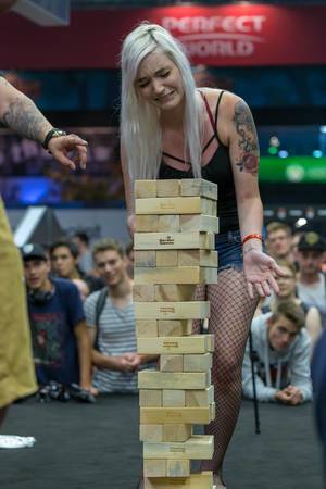Young woman removing blocks from a Jenga tower at CaseKing booth at Gamescom 2018