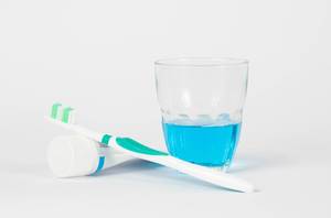 Zahnbürste, Zahnpaste und Mundspülung vor weißem Hintergrund