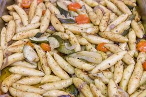 Zucchini-Schupfnudelpfanne mit Gemüse und Zwiebeln im Wärmebehälter am Büfett in der Nahaufnahme