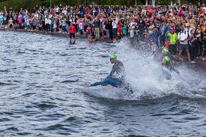 Zuschauer am Rand des Vesijärvisees feuern die Ironmansportler für den Schwimmwettkampf an