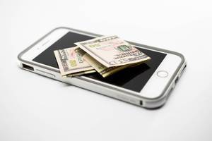 Zwei 50 US-Dollarnoten liegen auf Smartphone vor weißem Hintergrund