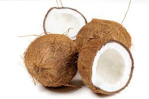 Zwei ganze und eine halbierte Kokosnuss auf weißem Hintergrund Nahaufnahme