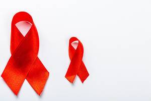 Zwei rote Bänder vor weißem Hintergrund symbolisieren den Kampf gegen Brustkrebs