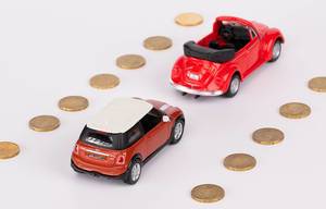Zwei rote Spielzeugautos fahren auf einer 20-Cent-Münzen-Straße