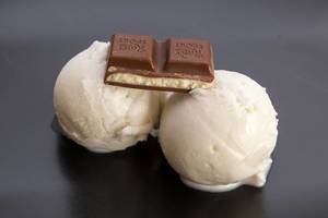 Zwei sojafreie und vegane Eiskugeln mit Kokosnussgeschmack von Nomoo und einem Stück gefüllter Schokolade von Ritter-Sport